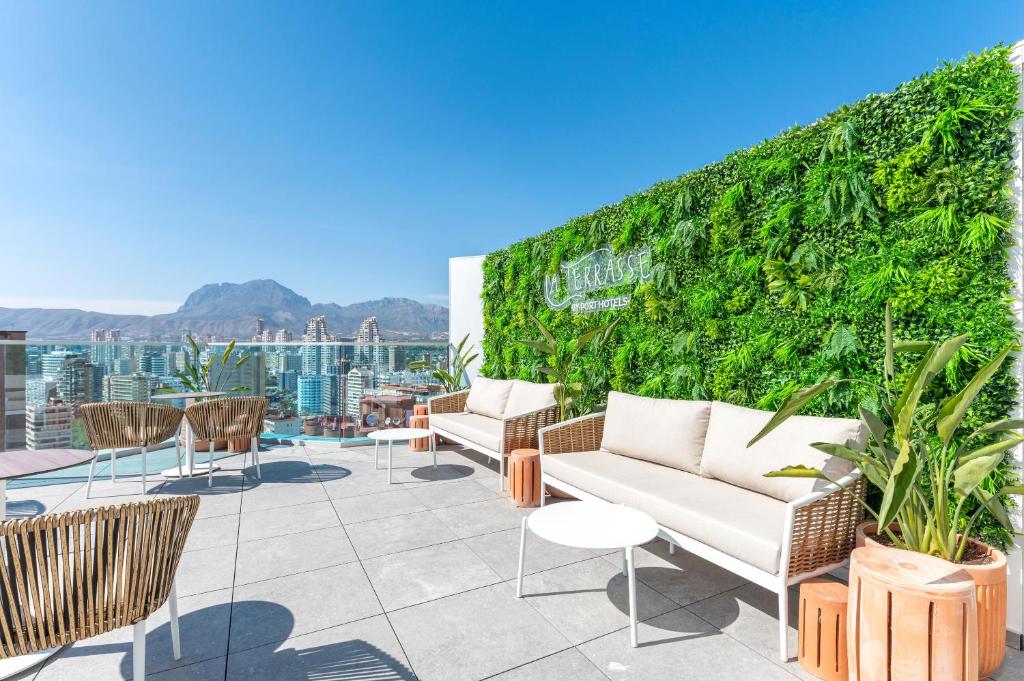 Mūsdienīgs terases dizains ar zaļo sienu un ērtām mēbelēm, kas piedāvā skatu uz pilsētu un kalniem. Ideāla vieta relaksācijai un atpūtai.