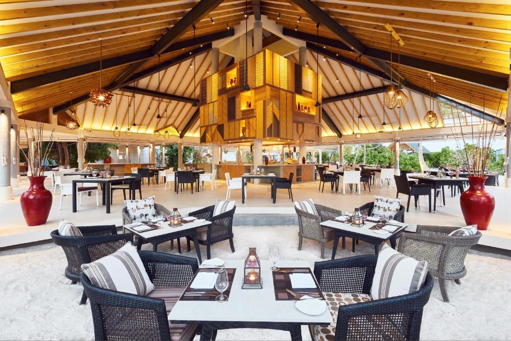 Mūsdienīgs restorāns ar plašu, atvērtu telpu, kas apgaismota ar siltu gaismu. Centrā ir eleganta barista zona, bet ap to ir izsmalcināti galdi un krēsli, kas gaida viesus.