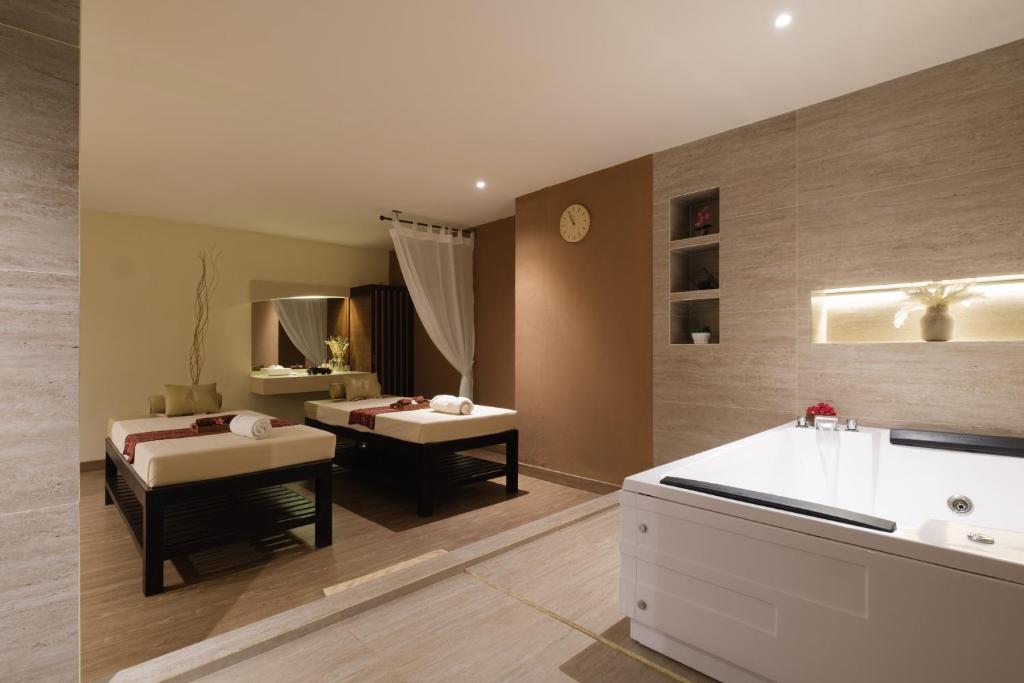 Mūsdienīgs spa interjers ar masāžas gultām, vannu un relaksējošu atmosfēru. Telpa ir gaiša un eleganta, radot mierīgu noskaņu.