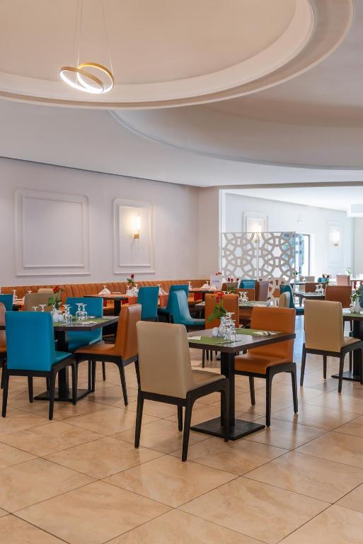 Mūsdienīgs restorāns ar krāsainām mēbelēm, kas rada patīkamu atmosfēru, ideāla vieta ēdienreizēm un sociālām tikšanām. Galdi ir sakārtoti ar ziediem un glāzēm, piedāvājot elegantu interjeru.