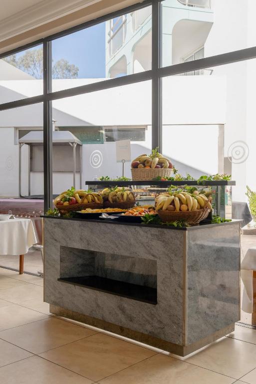 Svaigu augļu bufete ar dažādām augļu groziem, kas izvietota mūsdienīgā restorānā ar lieliem logiem. Gaisīgs un elegants interjers.