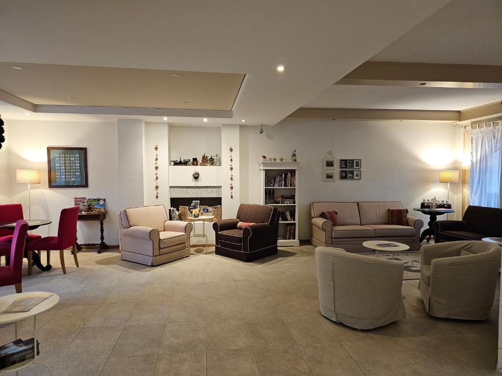 Mūsdienīgs un gaišs dzīvojamās telpas interjers ar dažādiem sēdvietu modeļiem un apgaismojumu. Telpā ir grāmatu plaukts un dekoratīvi elementi, radot mājīgu atmosfēru.