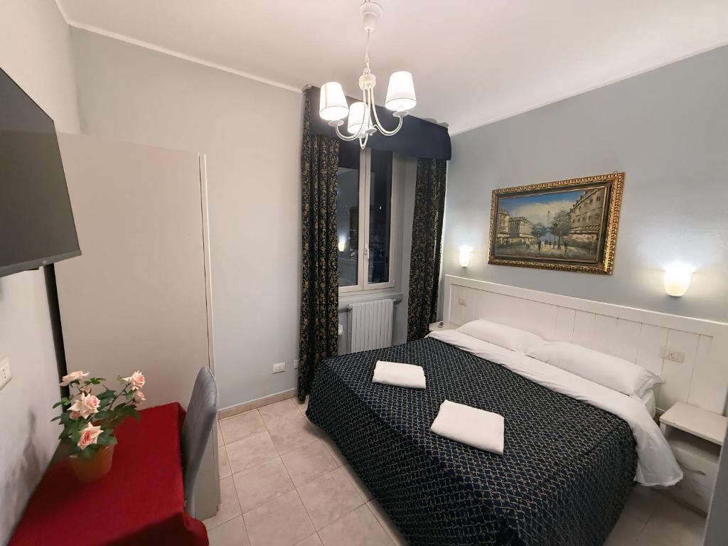 Mūsdienīgs guļamistabas interjers ar divguļamo gultu, televizoru un mākslas darbu uz sienas. Telpā ir eleganti aizkari un silta apgaismojuma elementi.