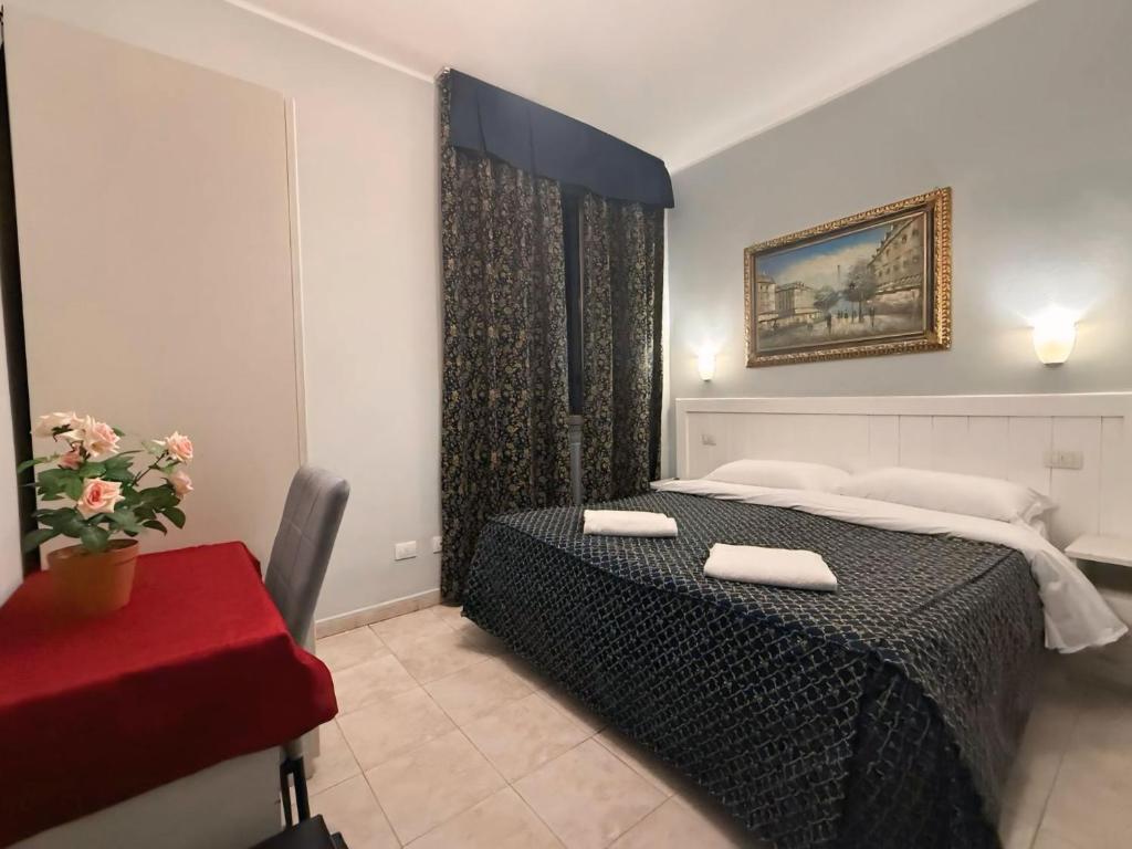 Mūsdienīgs viesnīcas numurs ar divguļamo gultu, elegantiem aizkariem un gleznainu ainu pie sienas. Telpas iekārtojums ietver ērtu rakstāmo un ziedu podu.