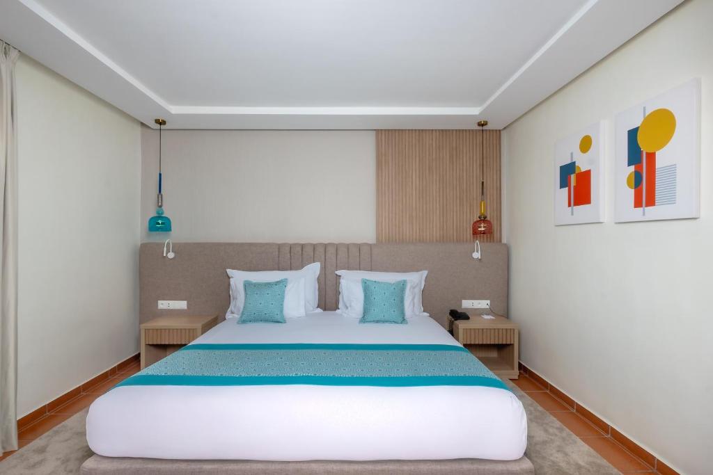 Mūsdienīga guļamistaba ar divguļamo gultu, korotā ar krāsainiem aksesuāriem un gaismas avotiem, radot relaksējošu atmosfēru. Uz sienas redzami moderni mākslas darbi.