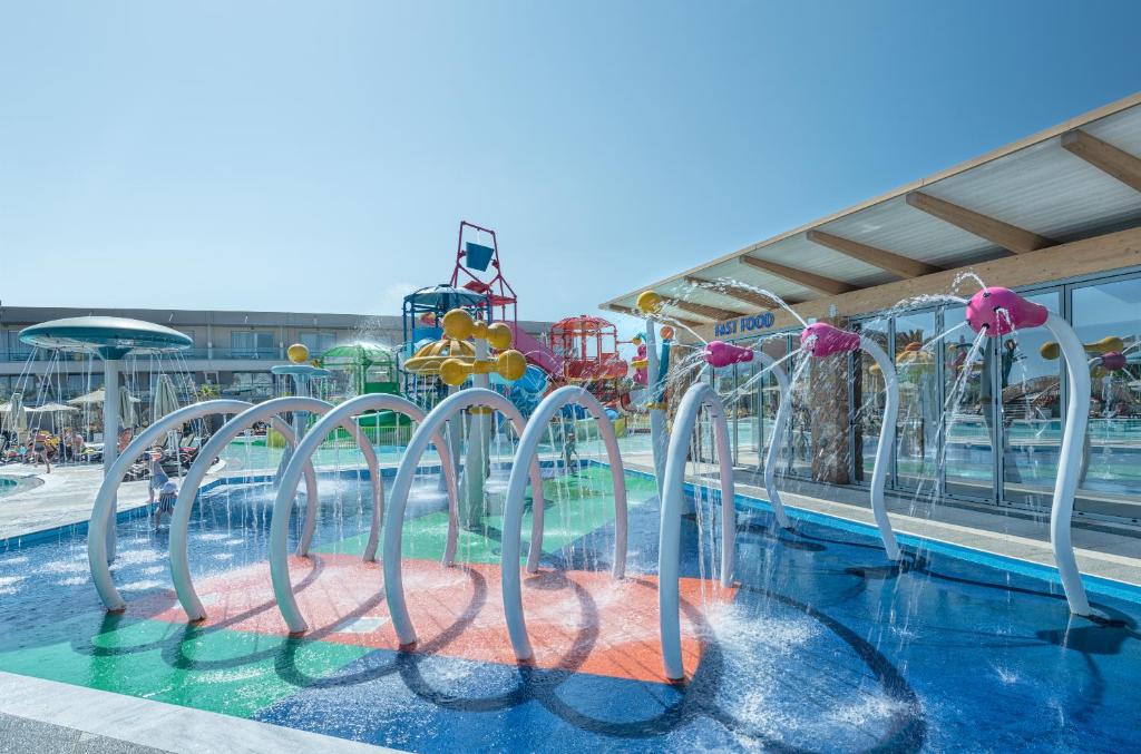 Ūdens atrakciju parks ar spilgtām krāsām un izklaidējošām ūdens strūklām, ideāls bērniem un ģimenēm. Saulaina diena un daudz vietas atpūtai.