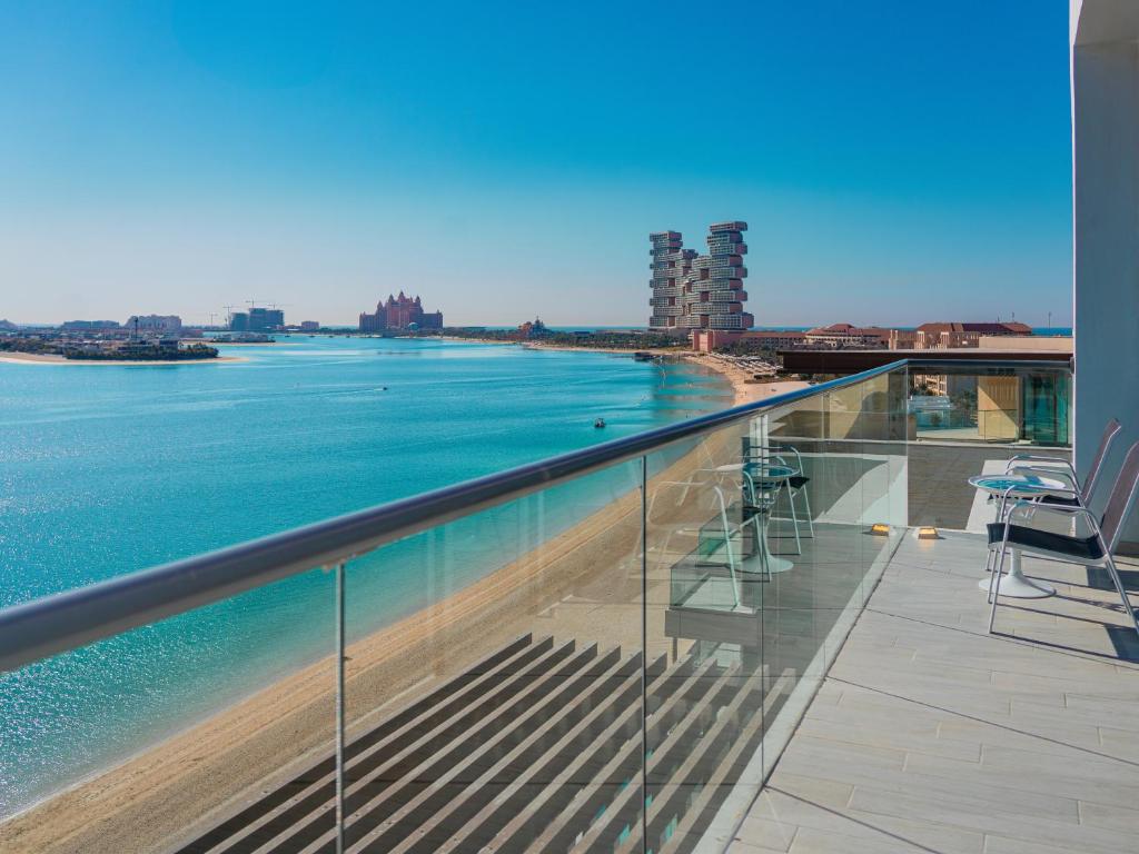 Skats no balkona uz mierīgu ūdeni un pludmali, ar modernām ēkām fona. Ideāla ainava relaksējošai atmosfērai.