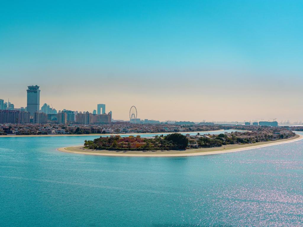 Skats uz pilsētu un pludmales salu ar skaidru zilo ūdeni un modernām ēkām fona.