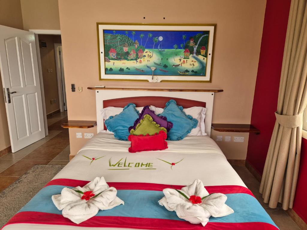 Gultas ar spilveniem un dvieļiem, kas veidoti ziedu formā, istabā ar krāsainu sienu un gleznainu ainavu. Uz palodzes atrodas mājīga atmosfēra un viesmīlības sajūta.