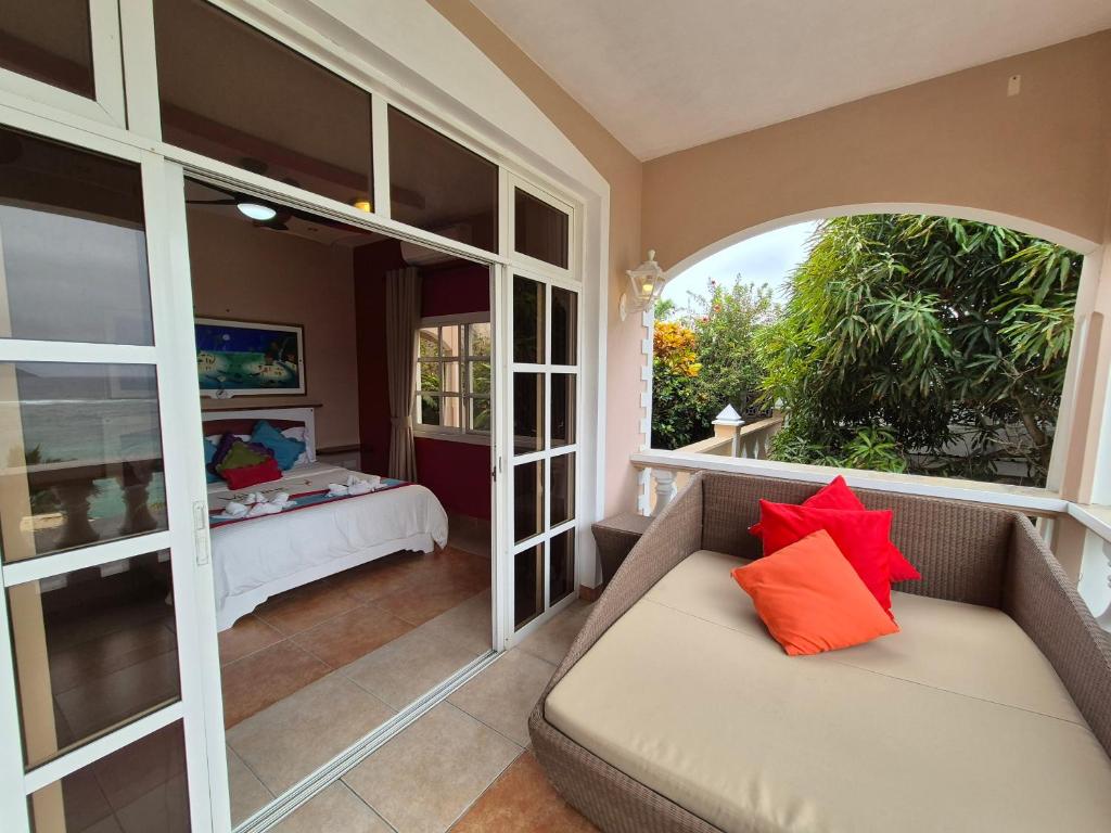 Mūsdienīgs balkons ar ērtu dīvānu un spilveniem, kas piedāvā skatu uz guļamistabu un dārzu. Ideāla vieta relaksācijai un atpūtai.