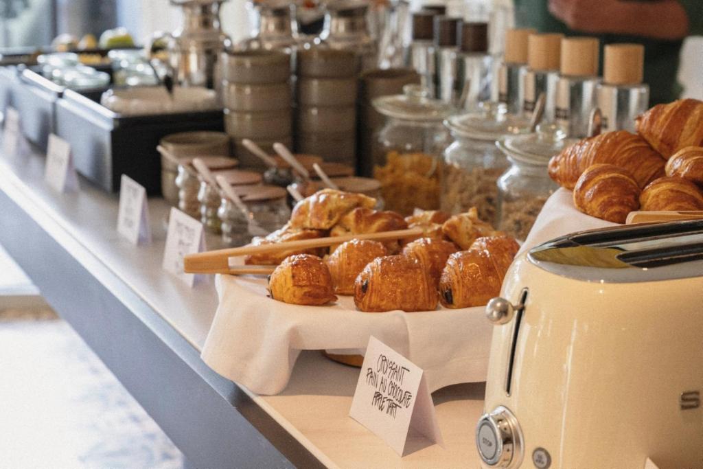 Brokastu galds ar dažādiem croissant un gardumiem, tostarp šokolādes croissant. Redzami arī rīki un uzglabāšanas trauki.