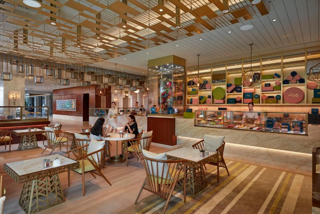 Moderns restorāna interjers ar elegantiem krēsliem, dekoratīvām lampām un krāsainām sienām, kur viesi baudīšanās brīdi.