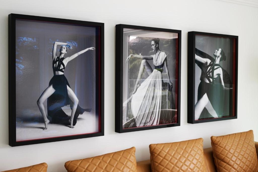 Trīs melnbaltas modes fotogrāfijas, kas ietvertas melnos rāmjos, parāda elegantas sievietes pozas. Fons ir gaišs un minimālistisks, savukārt zem fotogrāfijām ir brūnas, kvadrātveida spilveni.