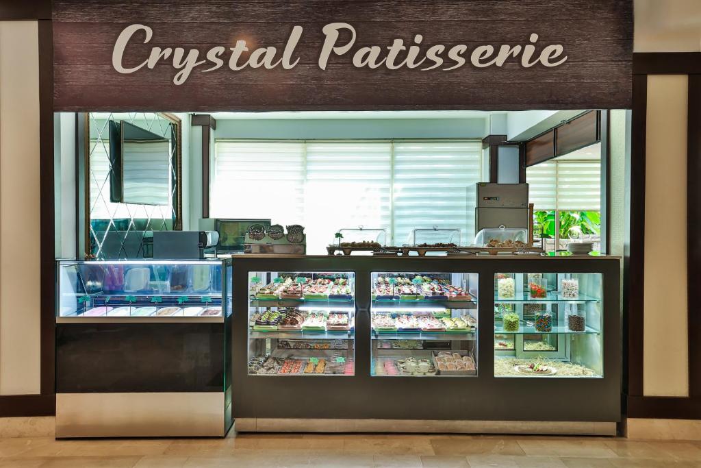Tīkla kiosks ar nosaukumu "Crystal Patisserie", kurā redzami dažādi konditorejas izstrādājumi un saldumi. Kiosks ir moderns un gaišs ar stikla vitrīnām, kas izceļ garšīgos kārumus.