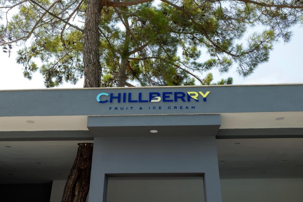 Chillberry zīme, kas piedāvā augļus un saldējumu, atrodas zem koka.