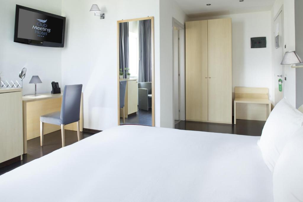 Moderns viesnīcas numurs ar gultu, rakstāmgaldu un televizoru, kas piedāvā ērtu un funkcionālu vidi. Telpa ir gaiša un eleganta, ar koka mēbelēm un mūsdienīgu apgaismojumu.