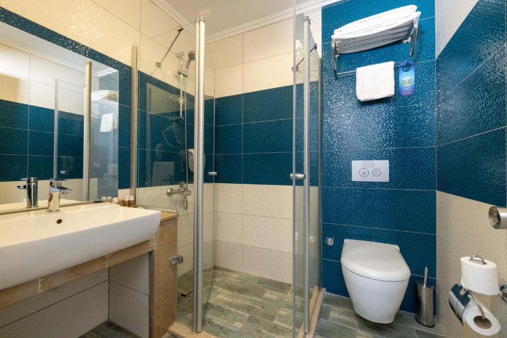 Mūsdienīgs vannas istabas interjers ar stikla dušas kabīni, izsmalcinātu izlietni un zilas flīzes. Vannas istaba ir aprīkota ar visām nepieciešamajām ērtībām.