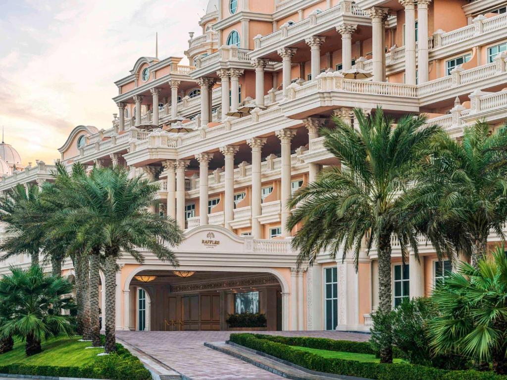 Elegants viesnīcas eksterjers ar greznām kolonnām un palmu stādījumiem. Šī arhitektūra izceļ krāšņo un modernu dizainu.