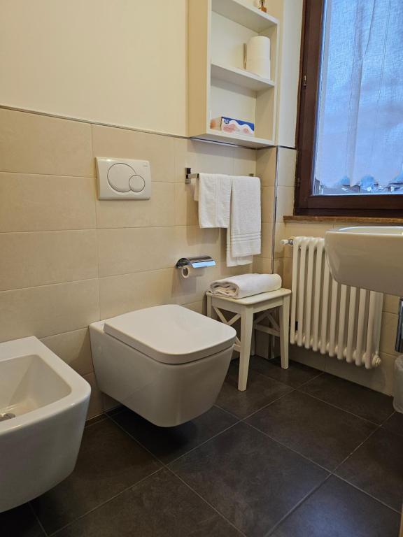 Mūsdienīga vannas istaba ar baltiem sanitārajiem izstrādājumiem, dvieļiem un radiatoru. Tumši flīžu grīda un gaišas sienas rada tīru un elegantu izskatu.