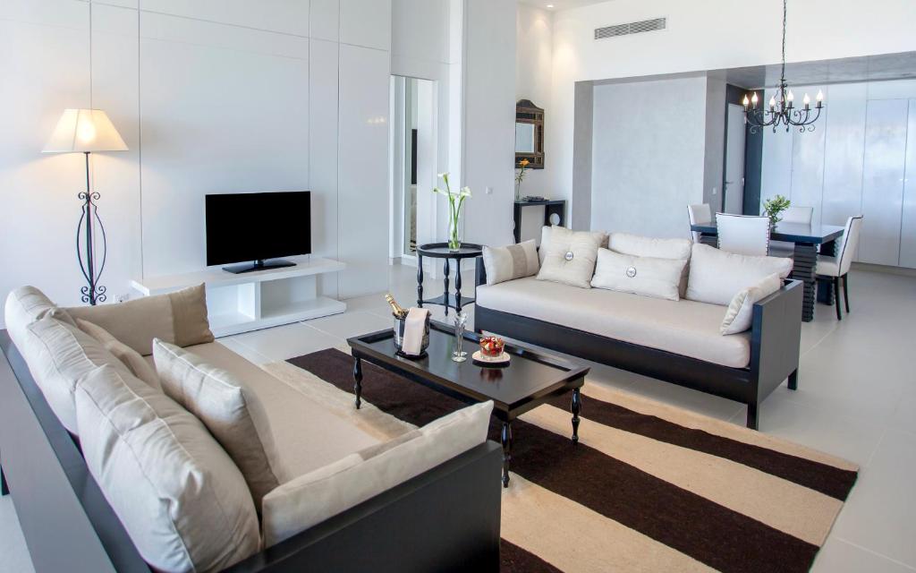 Mūsdienīgs viesistabas interjers ar diviem dīvāniem, melnu galdu un televizoru. Telpa ir gaiša ar elegantiem dekoriem un minimālistisku stilu.
