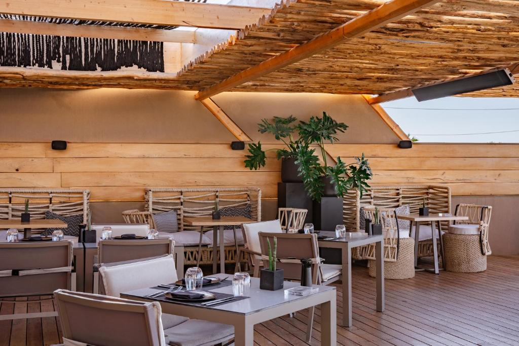 Elegants āra restorāns ar koka struktūru un modernu interjeru, kurā ir galdi un komfortabli krēsli. Zaļumi un mūsdienīga apgaismojuma elementi rada mājīgu atmosfēru.