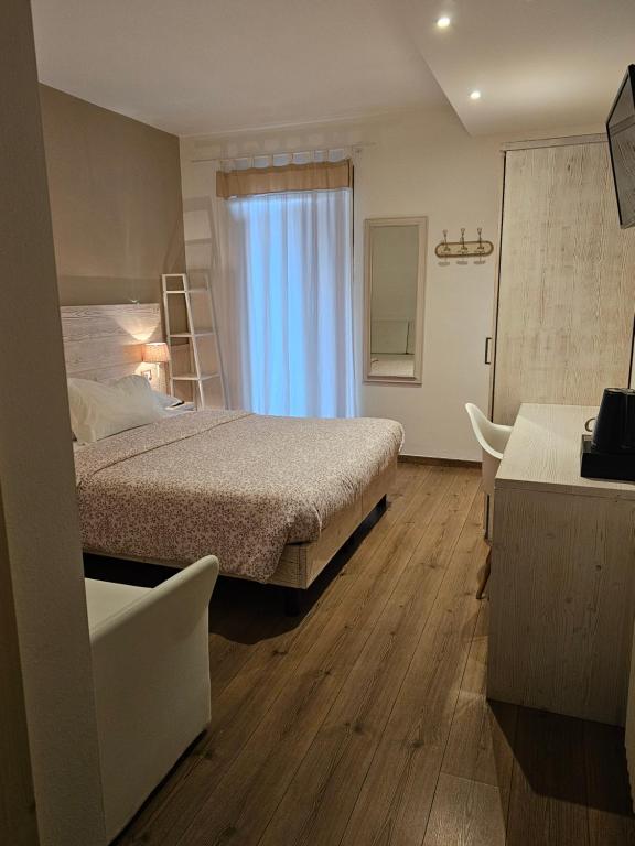 Mūsdienīga viesnīcas numura interjers ar divguļamo gultu, rakstāmgaldu un plašu logu, caur kuru ieplūst dabiska gaisma. Numurā ir arī spogulis un drēbju skapis.