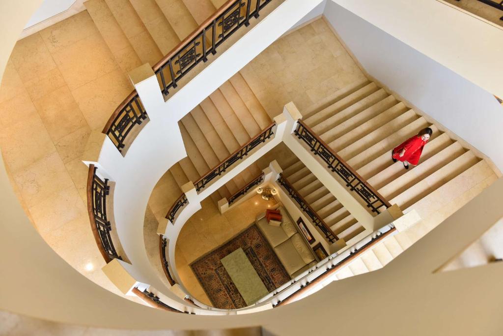 Elegantā spirālveida kāpņu telpa ar mīkstiem apgaismojumiem un mūsdienīgu dizainu. Skats no augšas uz kāpnēm un dzīvojamo telpu.