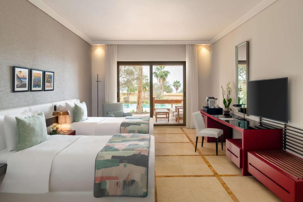 Mūsdienīgs viesnīcas numurs ar divām gultām, elegantu interjeru un piekļuvi terasei ar skatu uz baseinu un palmām. Numurā ir televizors un rakstāmgalds.