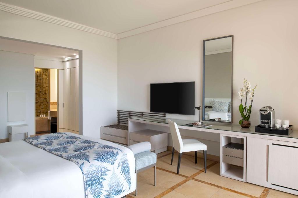 Mūsdienīgs viesnīcas numurs ar ērtu gultu, rakstāmgaldu un televizoru. Interjerā ir gaišas krāsas un dekoratīvas augu kompozīcijas.