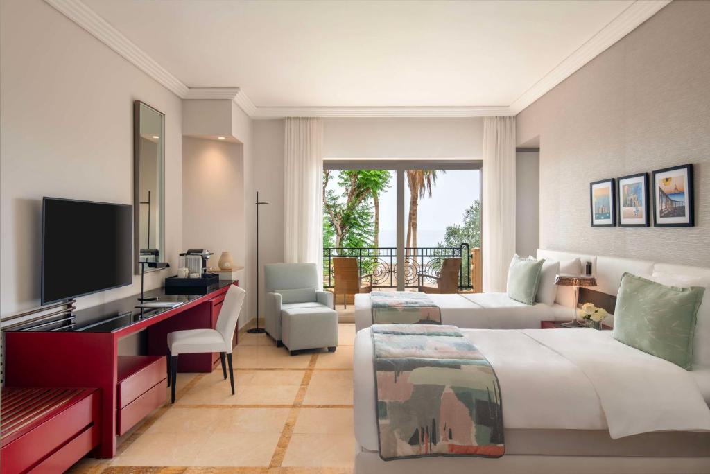 Mūsdienīgs viesnīcas numurs ar divām gultām, televizoru un skatu uz dabu. Telpā ir stilīgs dizains un ērti mēbeļi.