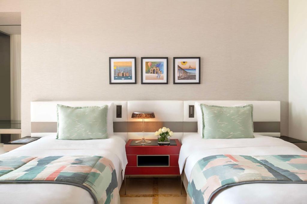 Mūsdienīgs viesnīcas numurs ar divām gultām, kas aprīkots ar stilīgu galdiņu un mākslas darbiem uz sienas. Numura dekors ir gaišās krāsās ar mīkstām spilveniem un elegantu apgaismojumu.