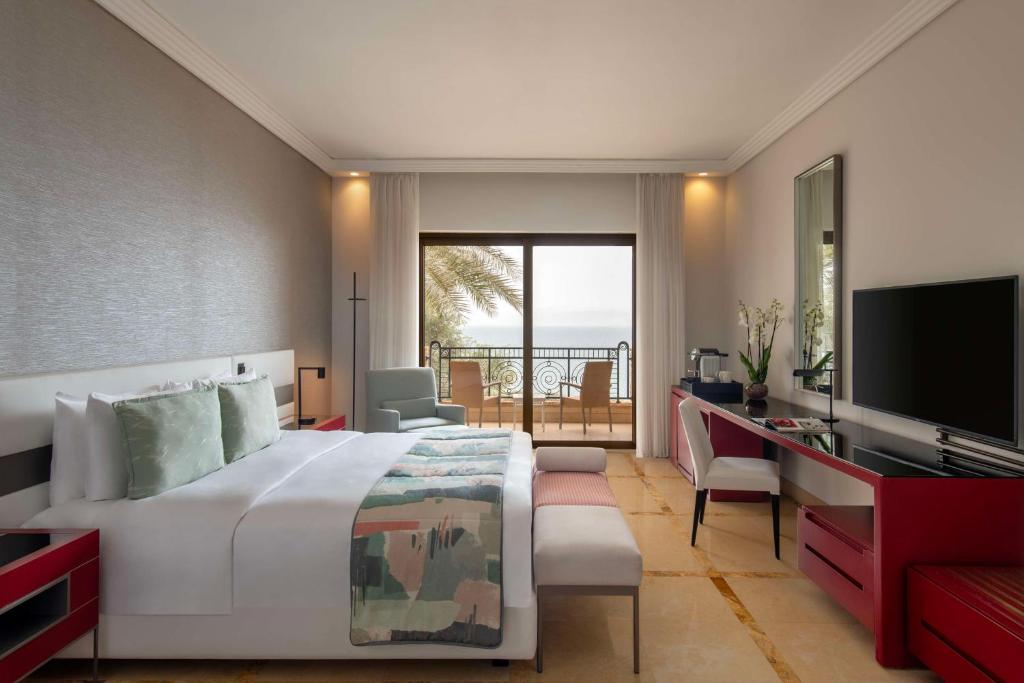 Mūsdienīgs viesnīcas numurs ar skatu uz jūru, iekārtots ar elegantu mēbelēm un komfortablu gultu. Telpā ir liela loga, kas nodrošina dabisko apgaismojumu un piekļuvi balkoniem.