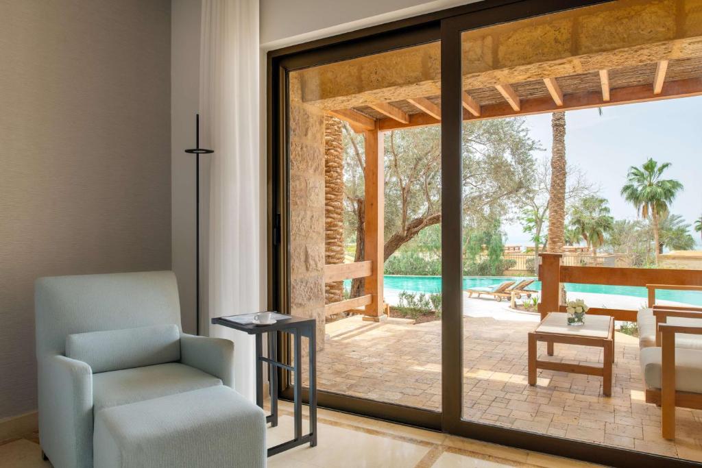 Mūsdienīgs interjers ar skatu uz terasi un baseinu, kurā ir palmām un gultām, kas aicina uz relaksāciju.