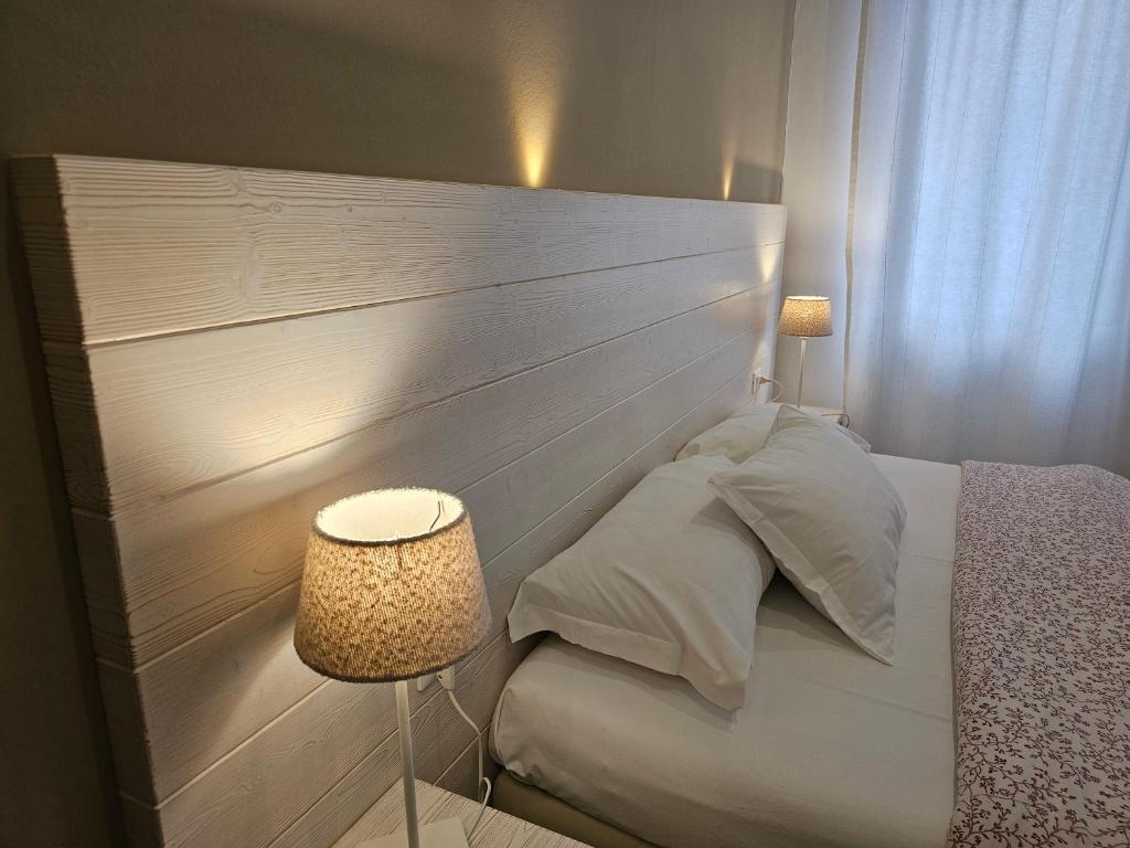 Mūsdienīgas guļamistabas interjers ar koka galvas dēli, spilveniem un gaismas lampām, radot siltu un mājīgu atmosfēru.