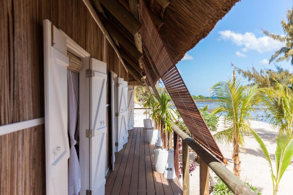 Balkons ar baltām durvīm un koka grīdu, kas ved uz pludmali ar palmām un jūras skatu. Ideāla vieta relaksācijai un atpūtai.