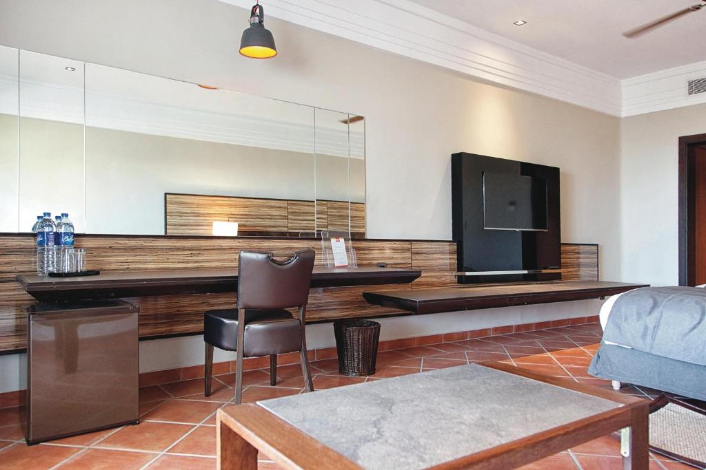 Mūsdienīgs viesnīcas numurs ar elegantām mēbelēm, darba galdu un televizoru. Telpa ir gaiša ar spoguļiem un siltu apgaismojumu.