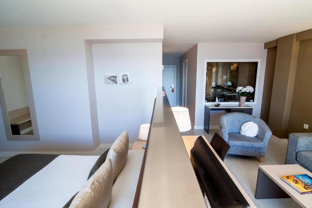 Mūsdienīga viesnīcas istaba ar atsevišķu atpūtas zonu, kurā ir dīvāns un galdiņš, un gaišām krāsām. Interjers ir gaumīgs un elegants, nodrošinot komfortablu atmosfēru.