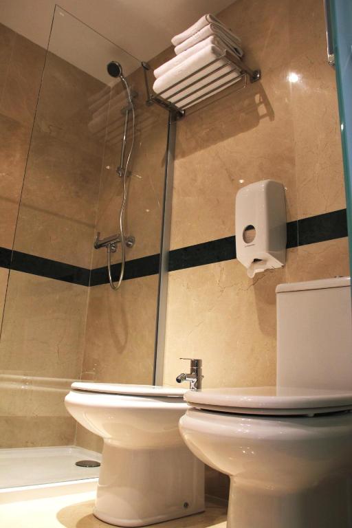 Mūsdienīgs vannas istabas interjers ar dušas kabīni, tualeti un uzglabāšanas plauktu ar dvieļiem. Elegants akmens apdare un higiēnas ierīces.