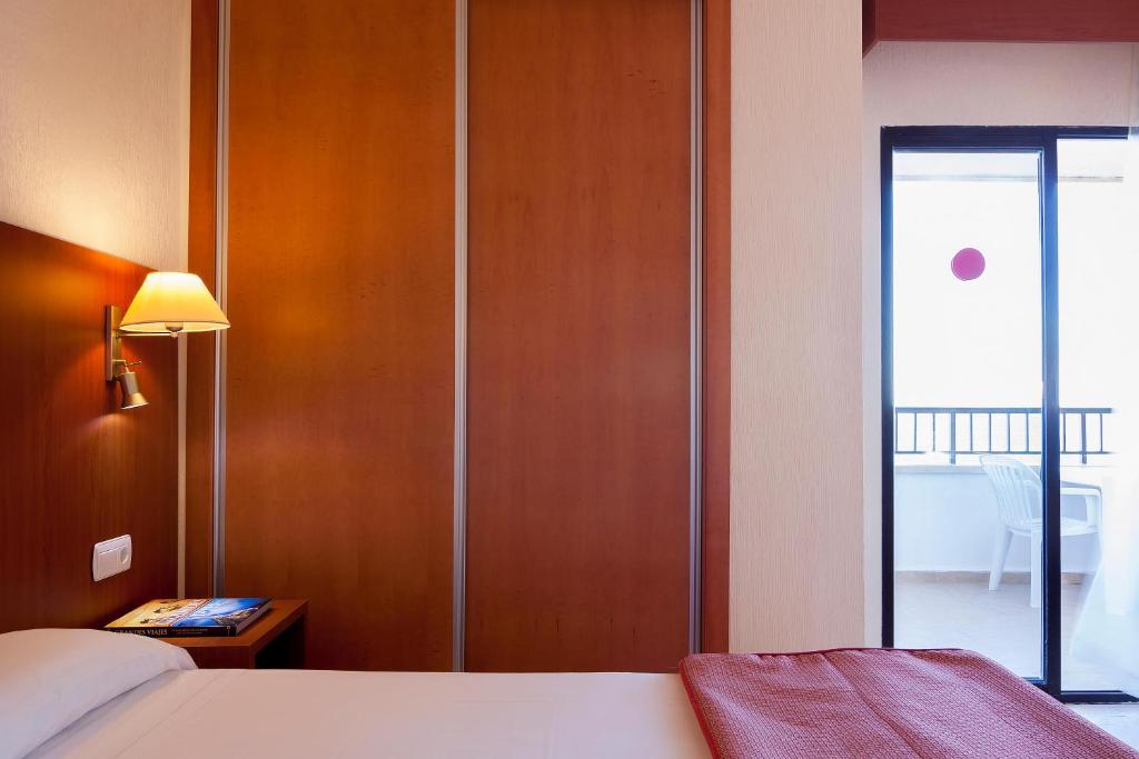 Mūsdienīgs viesnīcas numurs ar siltām krāsām un piekļuvi balkoniem. Gaismas avots un mēbelēta vieta rada mājīgu atmosfēru.