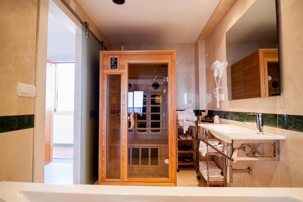Mūsdienīga vannas istaba ar saunu, spoguli un vannu. Telpā ir arī dvieļi un higiēnas piederumi.