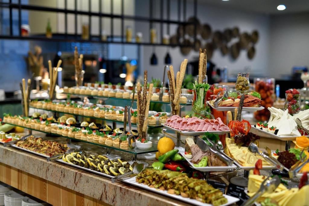 Bufete ar dažādiem uzkodu un ēdienu izkārtojumiem, tostarp dārzeņiem, gaļām un desertiem, kas vilina ar krāsām un garšām. Ideāls piedāvājums svinībām vai svētkiem.