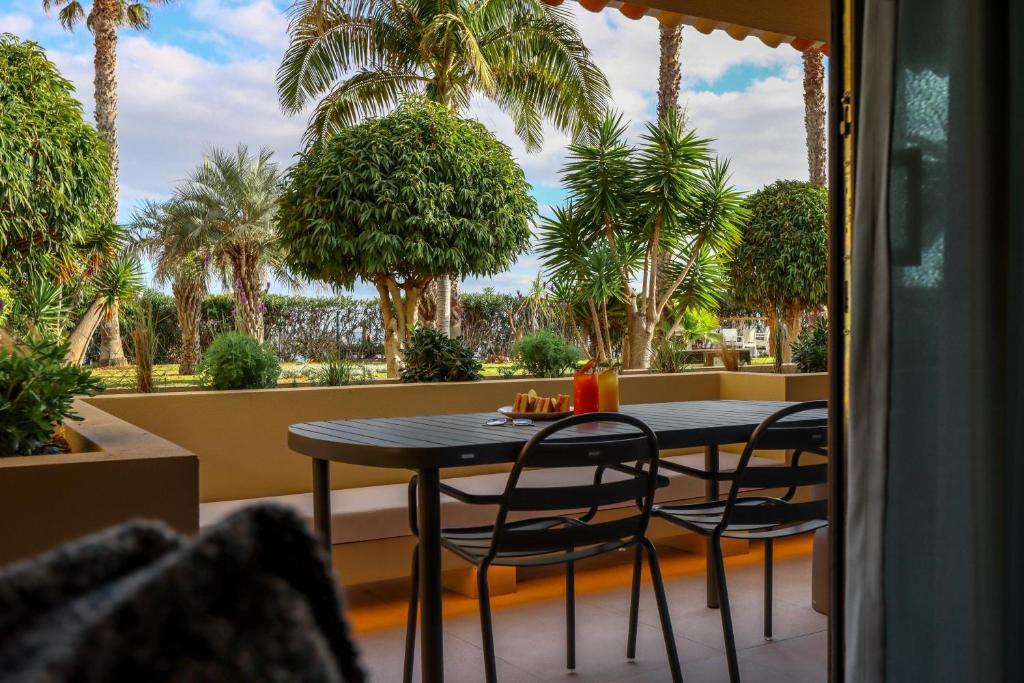 Terases skats uz zaļo dārzu ar palmām un krūmiem, kur uz galda atrodas dzērieni un uzkodas. Ideāla vieta relaksācijai un baudīšanai.