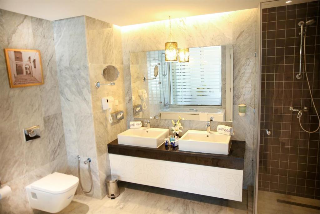 Moderns vannas istabas interjers ar divām izlietnēm, spoguli un dušas kabīni, apvienojot marmora un koka elementus. Eleganta un funkcionāla telpa.