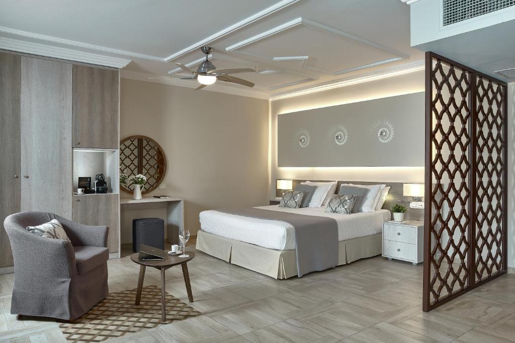 Mūsdienīgs numurs viesnīcā Knossos Royal ar ērtu gultu un sēdvietu.