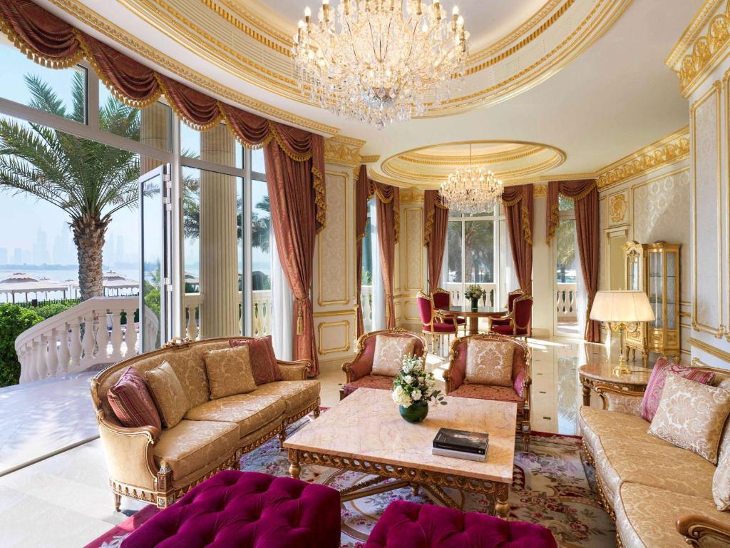 Greznas viesistabas interjers ar zeltītiem aksesuāriem, luksusa mēbelēm un panorāmas logiem, kas paver skatu uz ainavu. Atpūtas zona ir izrotāta ar elegantiem audumiem un gaismas ķermeņiem.