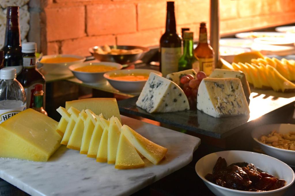 Siera un uzkodu galda izkārtojums ar dažādiem sieriem, augļiem un dzērieniem, radot patīkamu atmosfēru. Ideāli piemērots svinībām vai pasākumiem.