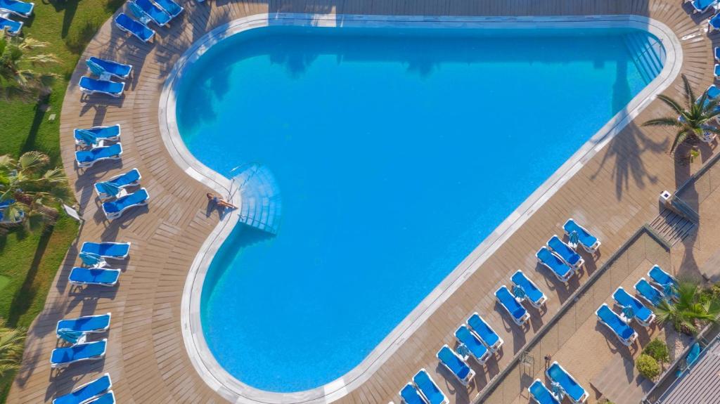 Sirds formas baseins ar zilu ūdeni un saulessargiem ap to, ideāli piemērots relaksācijai un atpūtai.