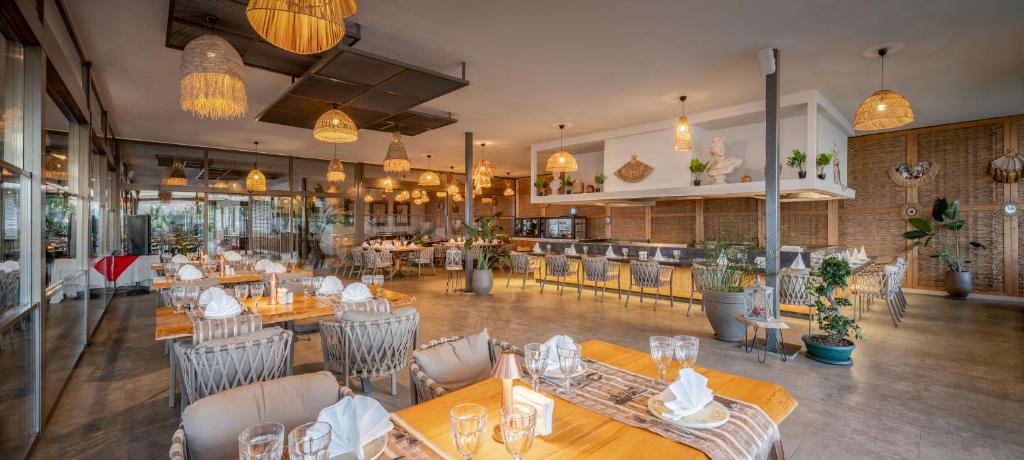 Mūsdienīgs restorāns ar elegantu interjeru, kas apgaismots ar stilīgām lampām un dekoratīvām augu kompozīcijām. Siltas krāsas un ērti galdi veido patīkamu atmosfēru.