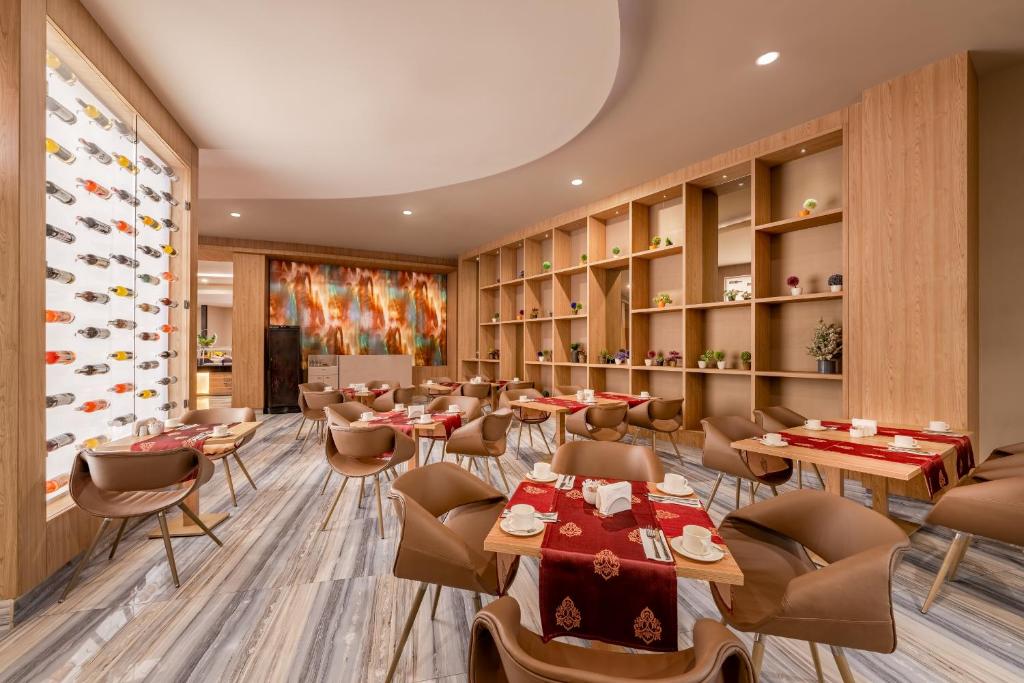 Mūsdienīga restorāna interjers ar koka elementiem, elegantām galdiem un krēsliem, kā arī dekoratīvām plauktiem. Uz galdiem redzami galda piederumi un rotājoši elementiem.