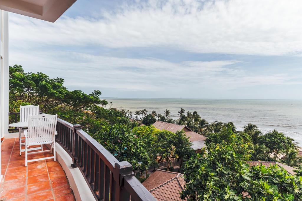 Skats no balkona uz okeānu un zaļajām palmu alejām, radot mierīgu un atpūtu veicinošu atmosfēru. Ideāla vieta relaksācijai un dabas baudīšanai.